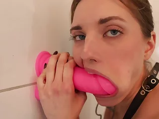 Teenage bitch is deep throating a giant rosy orgy toy that's stuck to a wall